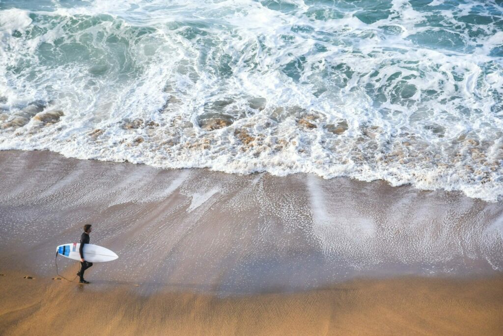 Surfer walking along the shore looking for the best surf spot
