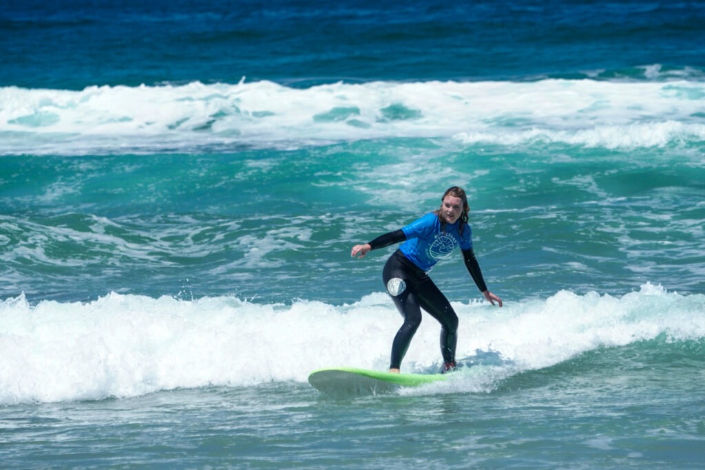 Young kid learning how to surf with Pacific Surf School.