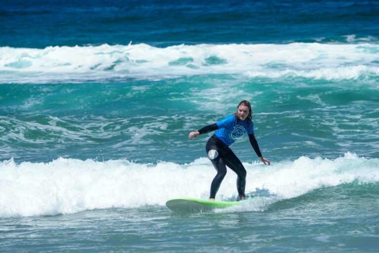 Young kid learning how to surf with Pacific Surf School.