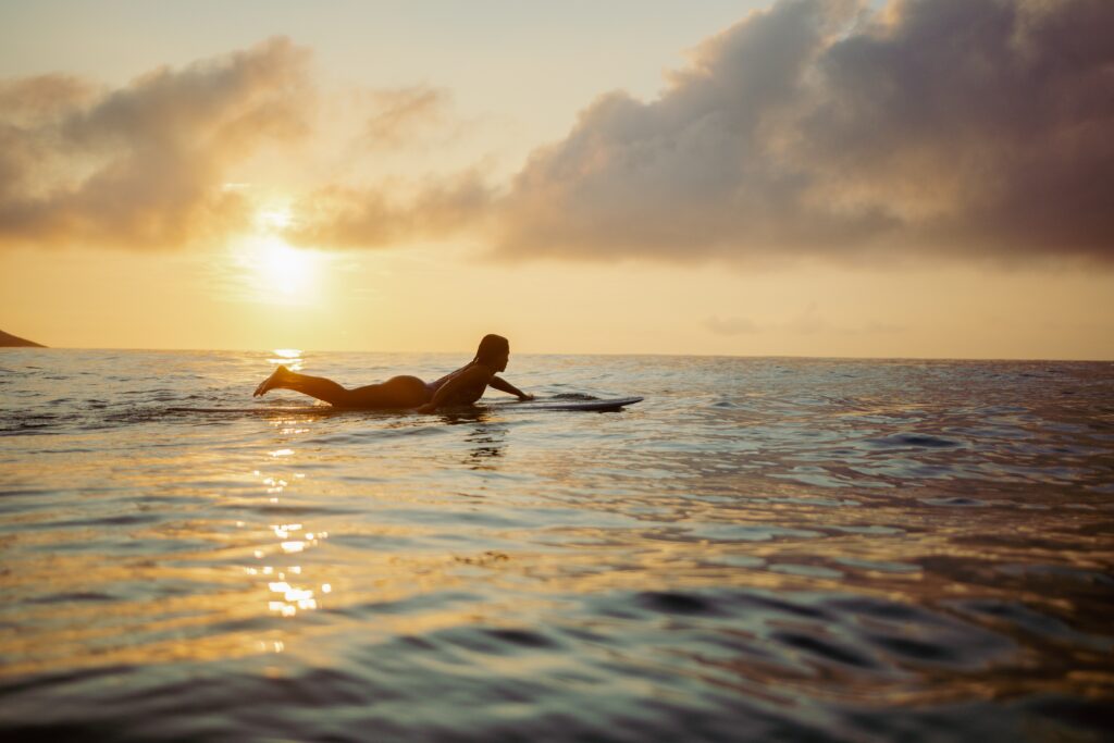 a person lying on a surfboard in the water