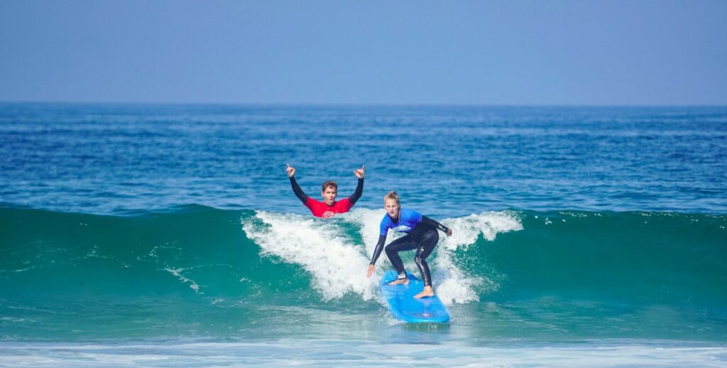 Surf instructor celebrating after a student catches a wave