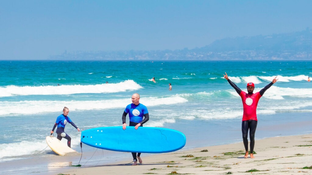 Surf instructor with students learning how to surf