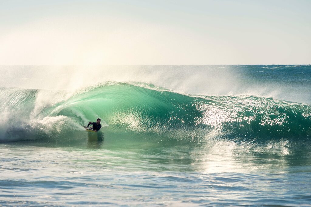 Surfer riding through a barrel wave on his stomach