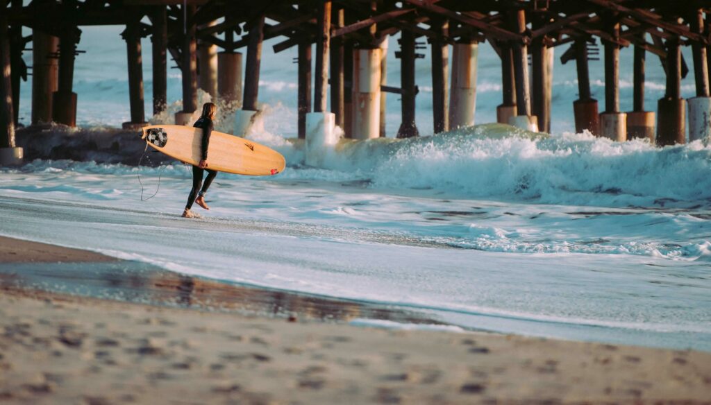 Man running into the ocean with his surfboard