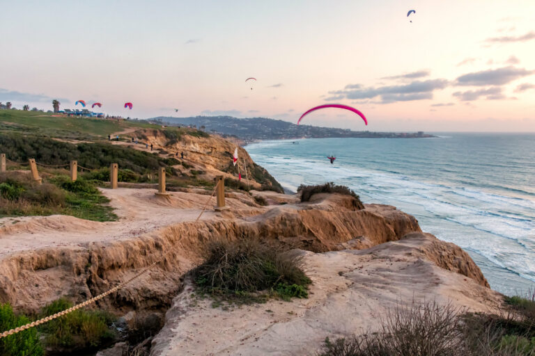 Hang glider hovering over sea cliff.