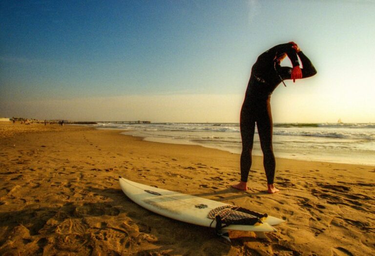 Person stretching on the beach before going surfing