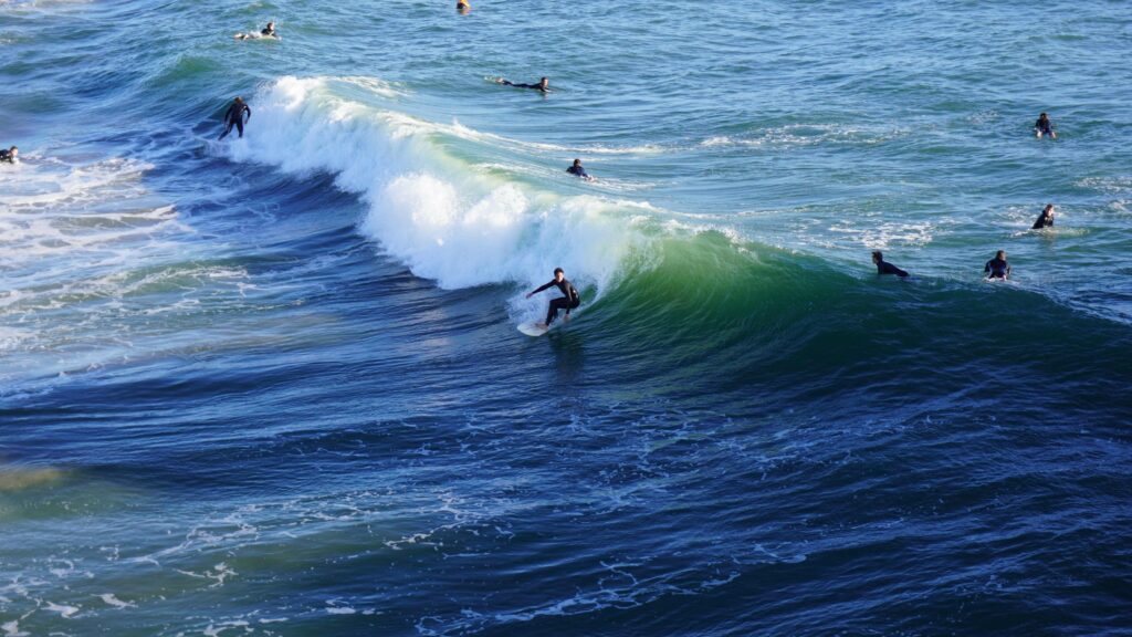 A group of surfers waiting to catch waves and practicing safe surf etiquette.