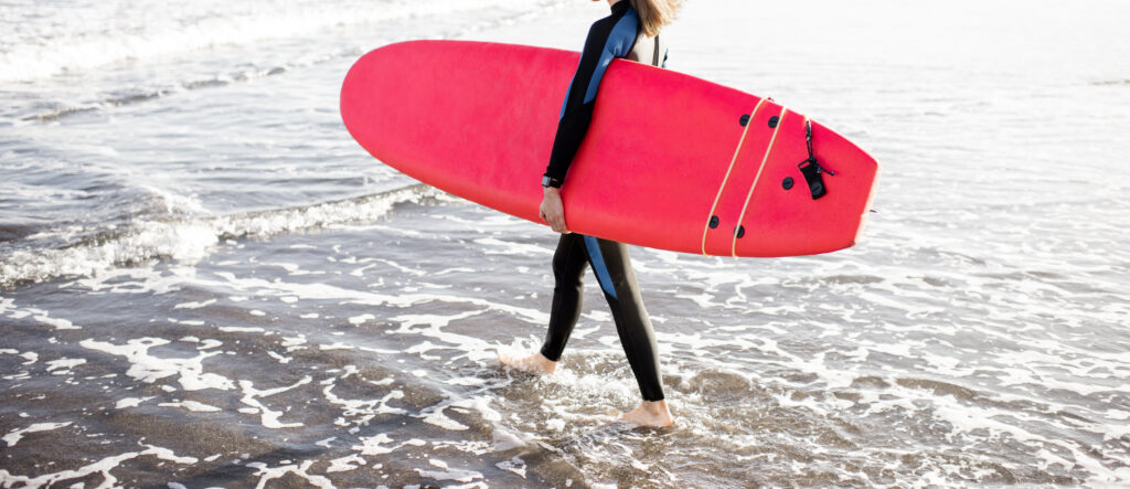 Woman holding a soft top surfboard, getting ready to go into the ocean