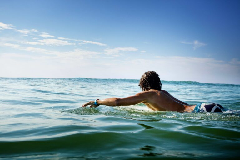 Man on a surfboard surfing safely in the water.
