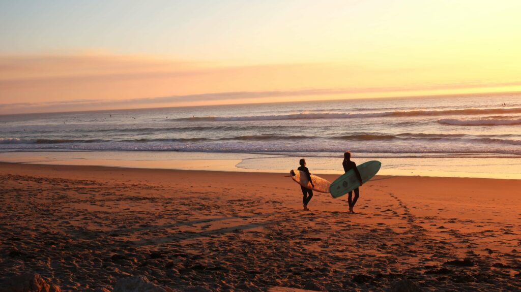 2 surfers holding their surfboards on the shoreline getting ready to go into the ocean.
