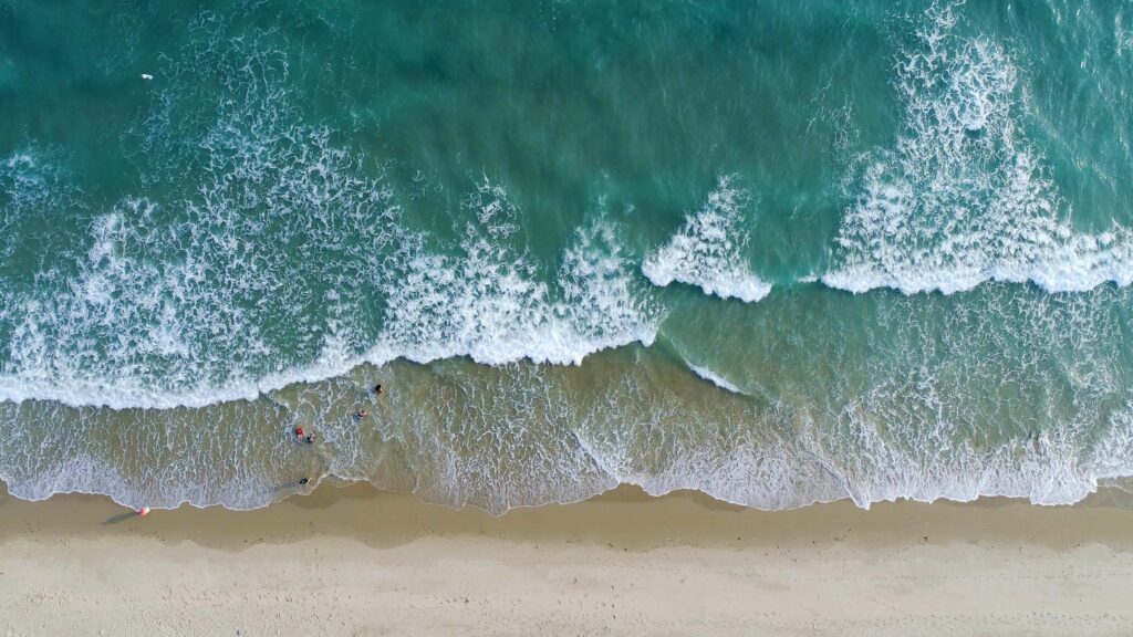 Aerial shot of waves breaking on a shoreline during low tide